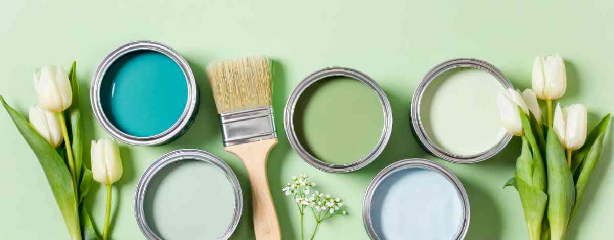Paint roller, brushes, tape, and color swatches surrounding a paint bucket near New York City