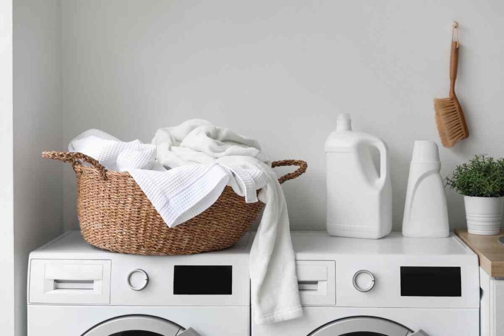 Basket with dirty clothes and detergent on washing machines in laundry room near New York City