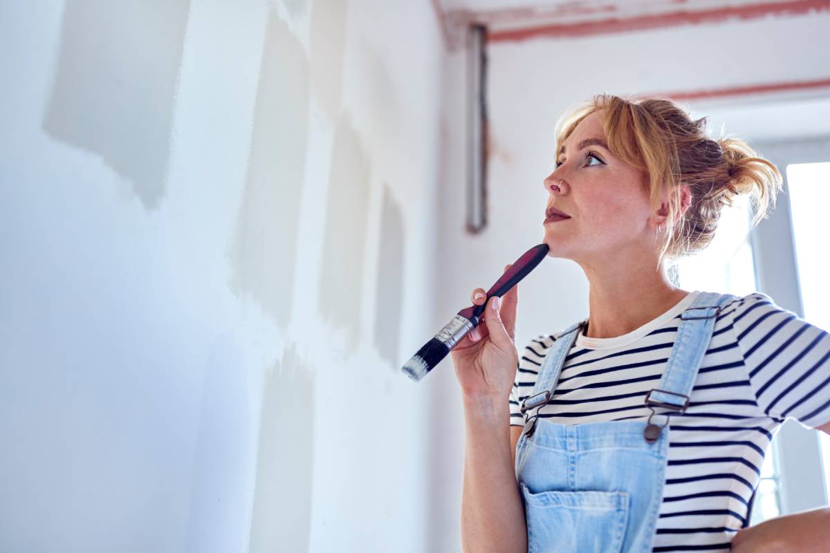 Woman starting at a wall comparing paint colors and sheens near New York City