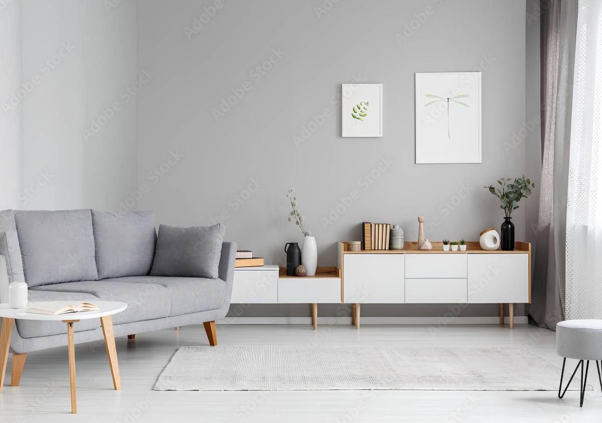 Grey settee near white cupboard in minimal living room interior with posters on the wall