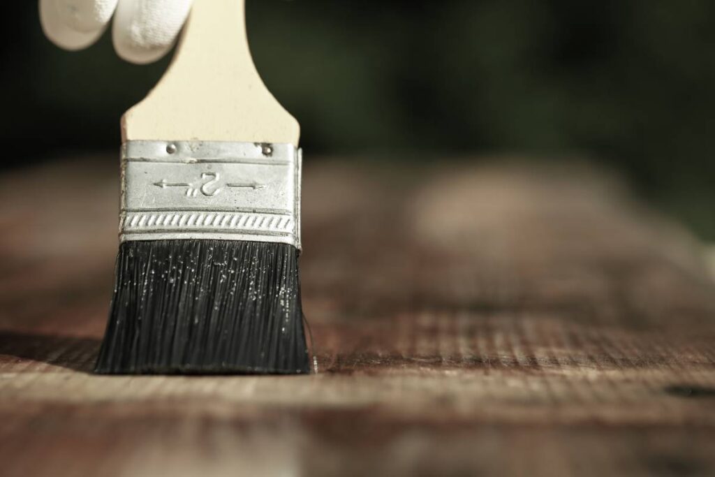 Paintbrush sliding over wooden surface at Janovic Paint & Decorating Center near NYC