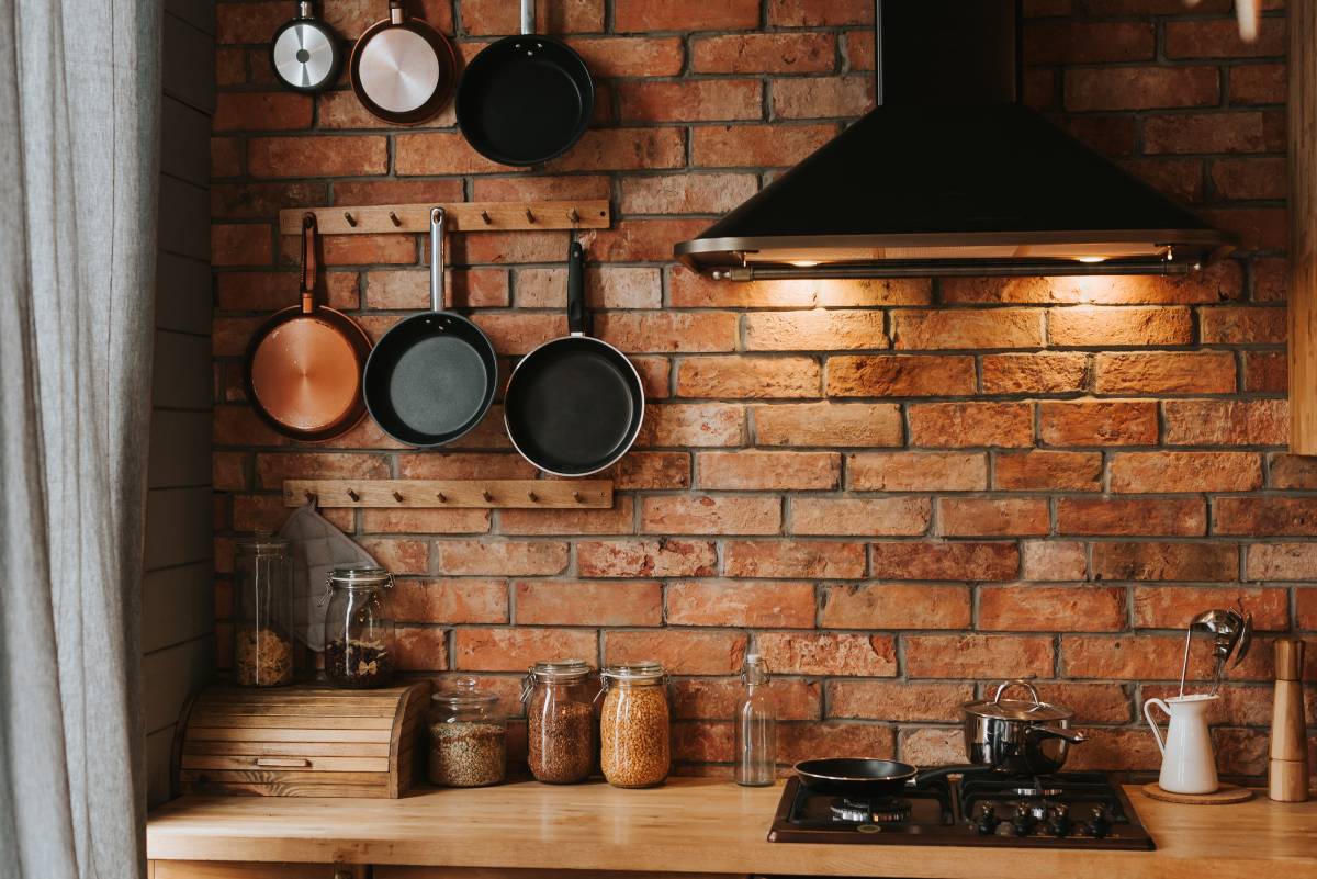 Cozy kitchen interior with pots and pans hanging on a brick wall